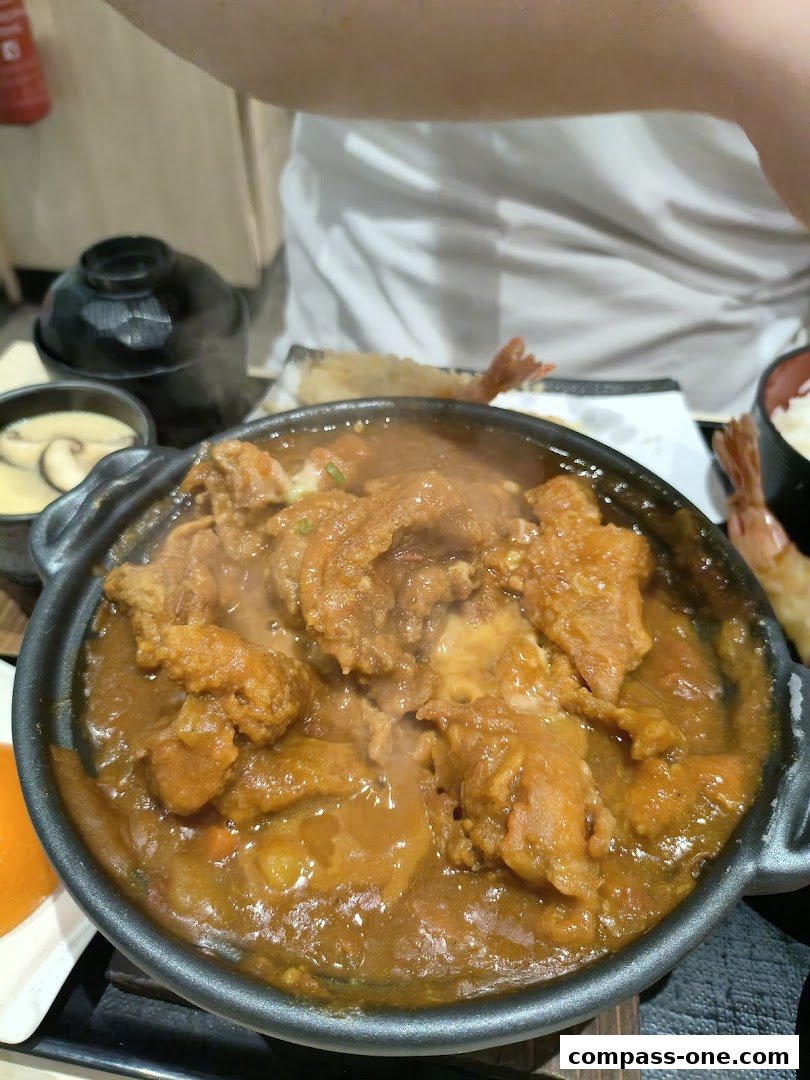 A close-up of a steaming Japanese curry dish with meat and vegetables.