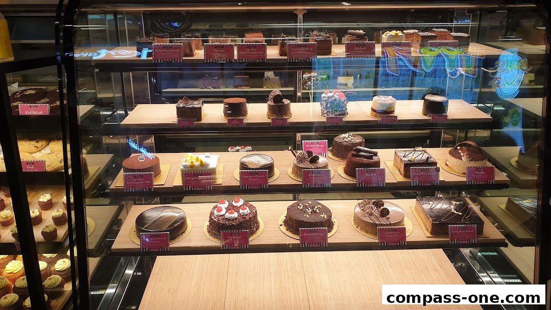 A display case filled with various beautifully decorated cakes and cupcakes.