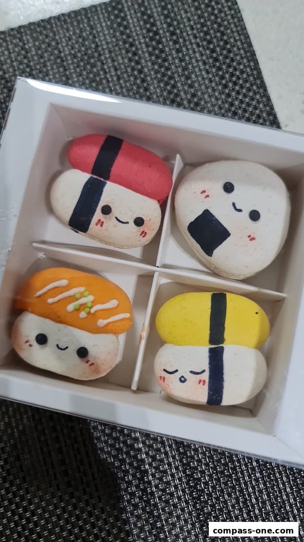 A box of four macarons decorated to look like sushi and onigiri.