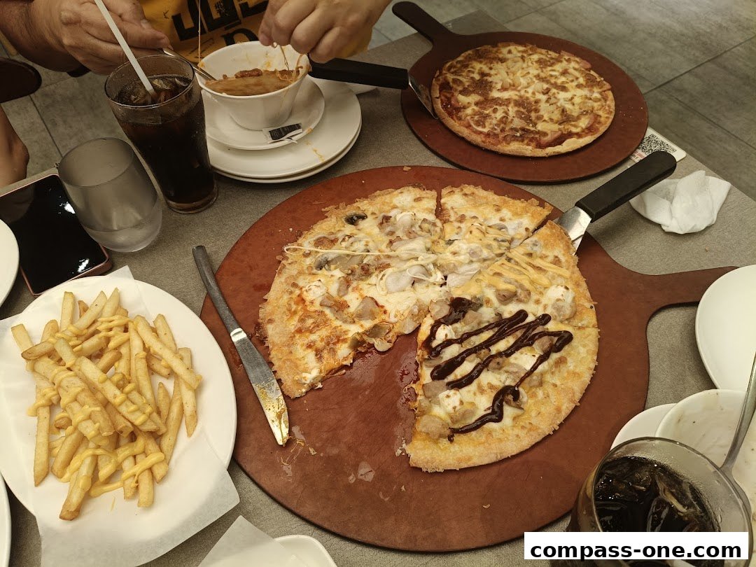 A table laden with pizzas, fries, and drinks, suggesting a meal at Pizza Hut.