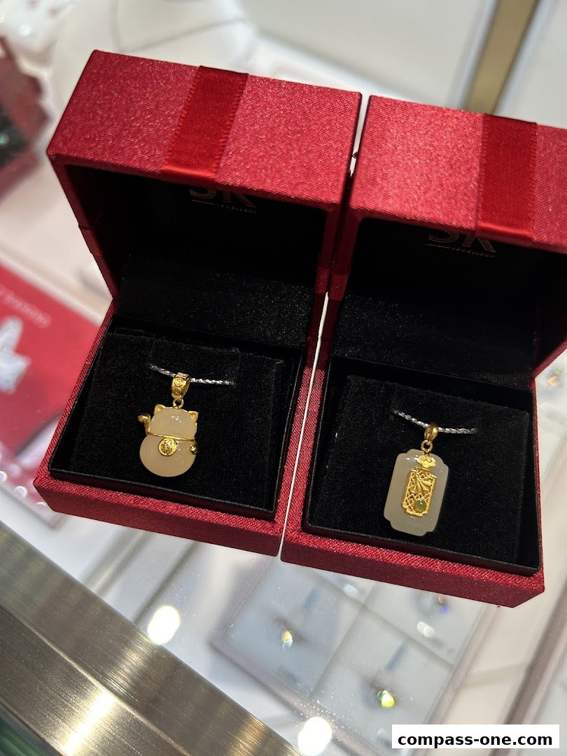 Two exquisite jade and gold pendants displayed in red gift boxes.
