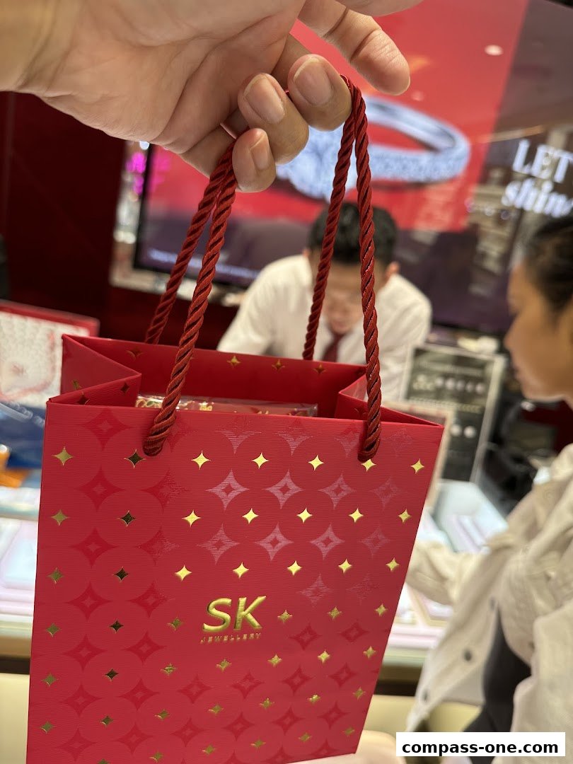 A hand holds a red SK Jewellery gift bag with gold star patterns.
