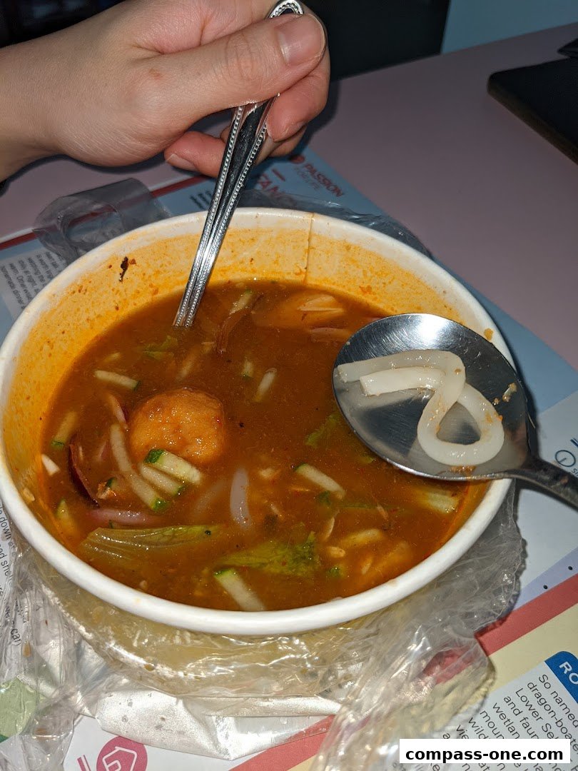 A close-up of a bowl of Laksa with a spoon scooping up noodles.
