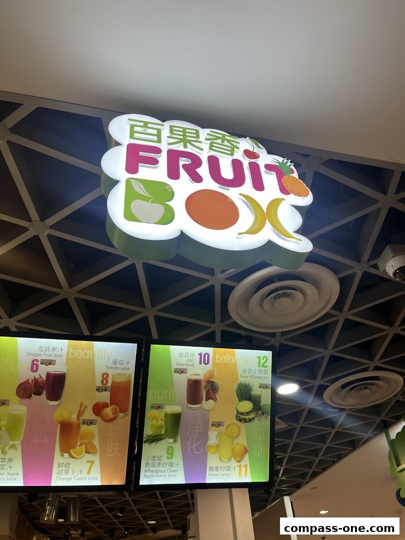 A brightly lit sign for 'Fruit Box' with a menu displaying various fruit juices.