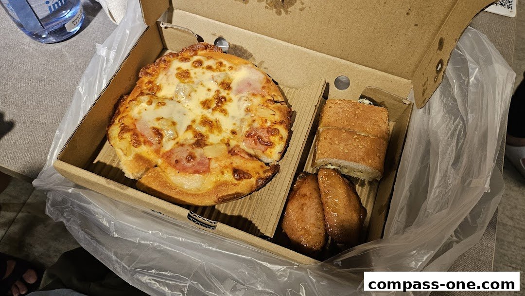 A Pizza Hut meal box containing a small pizza, breadsticks, and chicken wings.
