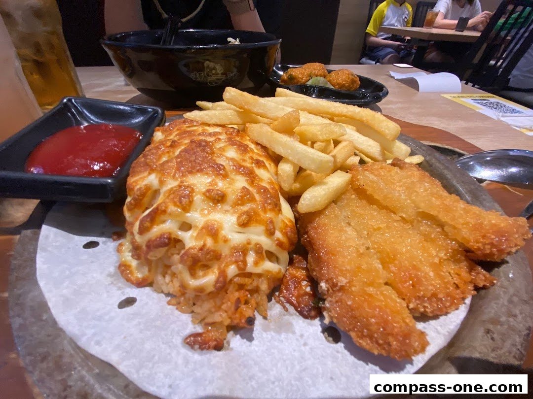 A close-up of a delicious meal featuring cheesy baked rice, crispy fried chicken, and french fries.