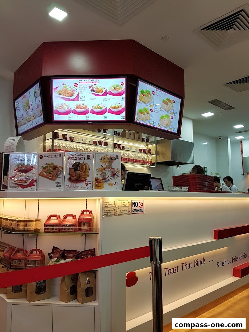 Interior view of Ya Kun Kaya Toast showing digital menus, counter, and retail shelves.