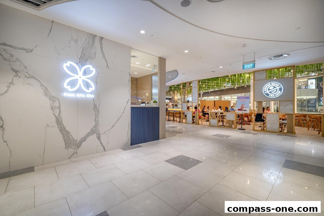 The entrance to Pixie Nail Spa with a marble wall and logo, next to a busy cafe.