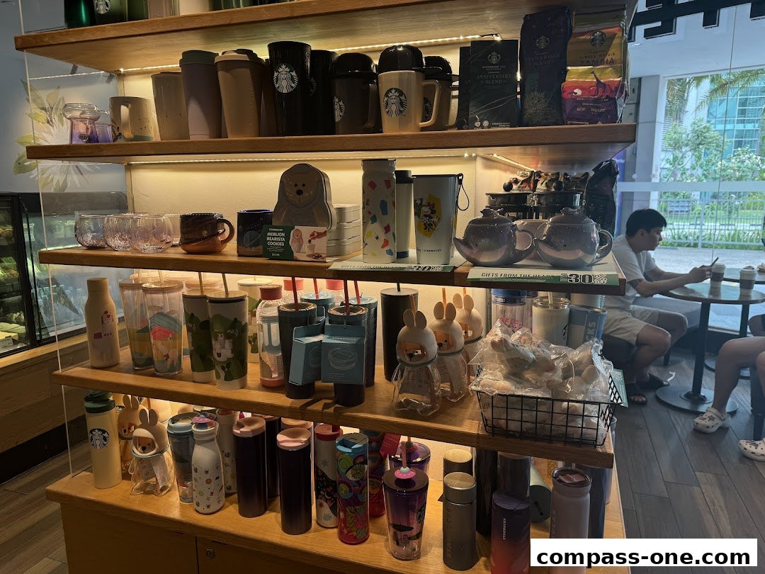 Shelves filled with Starbucks merchandise, including mugs, tumblers, coffee bags, and teapots, with customers seated in the background.