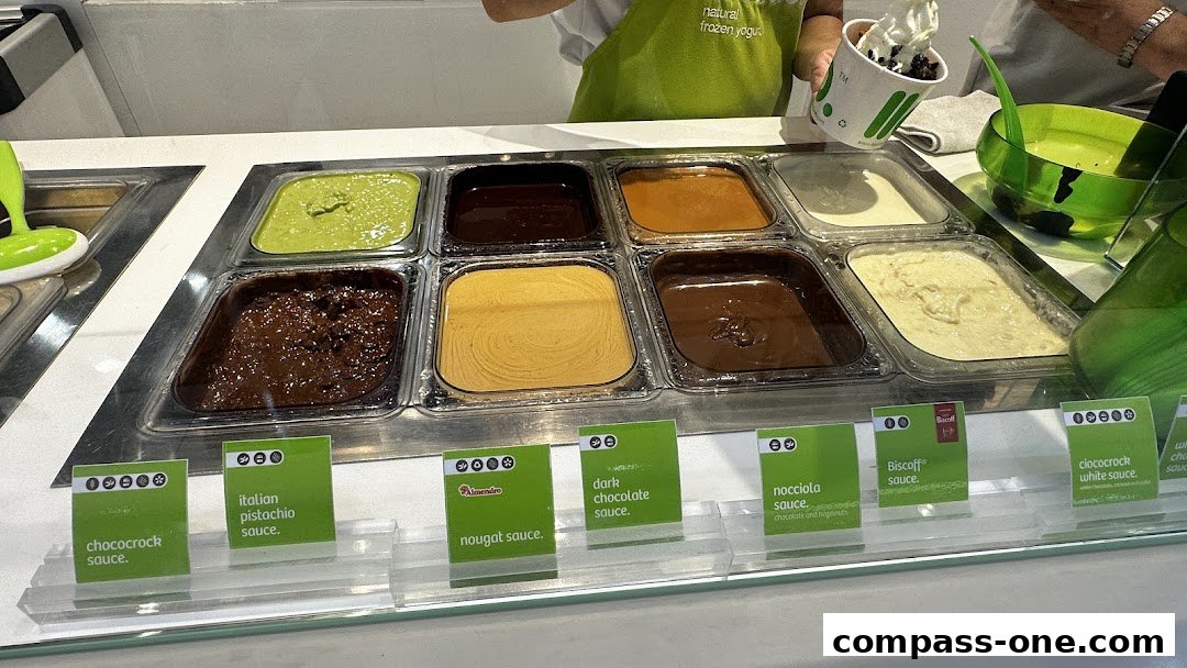 A display of various frozen yogurt sauces and toppings at a llaollao shop.