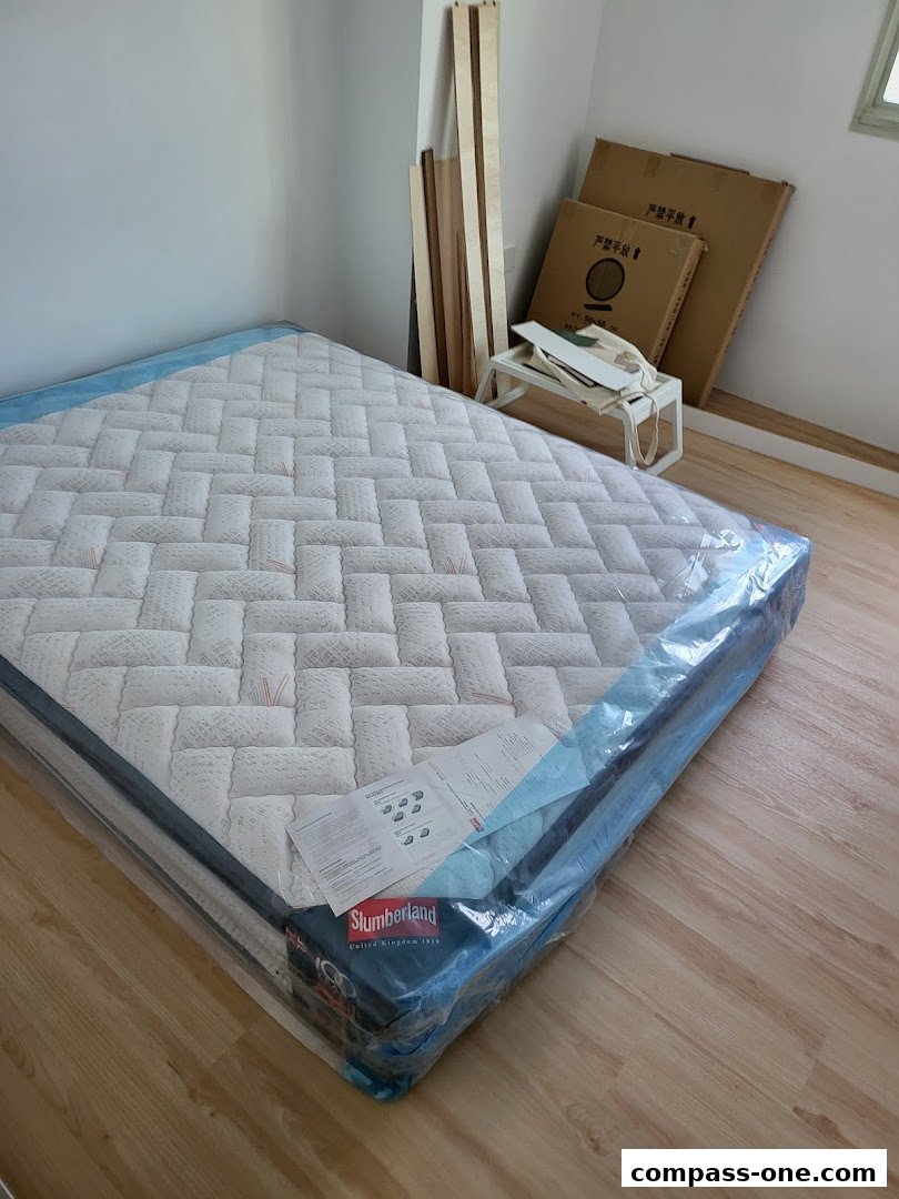 A new Slumberland mattress is displayed in a room with wooden flooring and some boxes in the background.