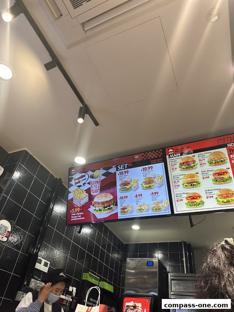 A digital menu board displaying various burger sets and individual burgers with prices.