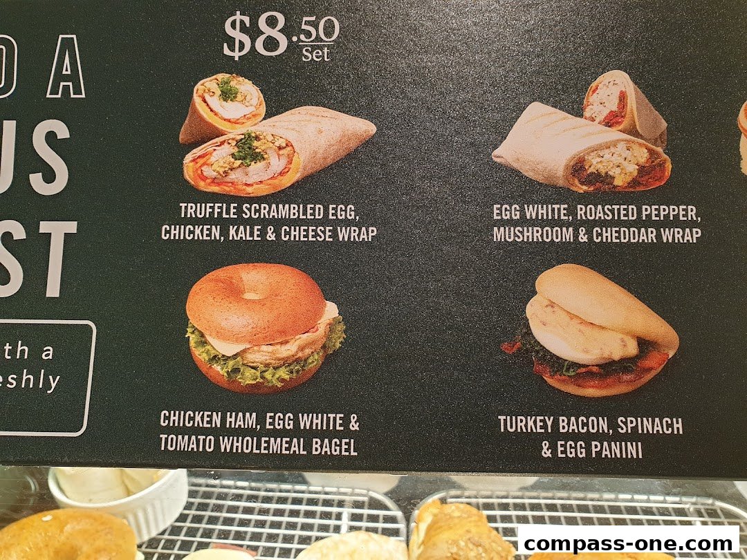 A menu board displaying various wraps, bagels, and paninis with their names and images.