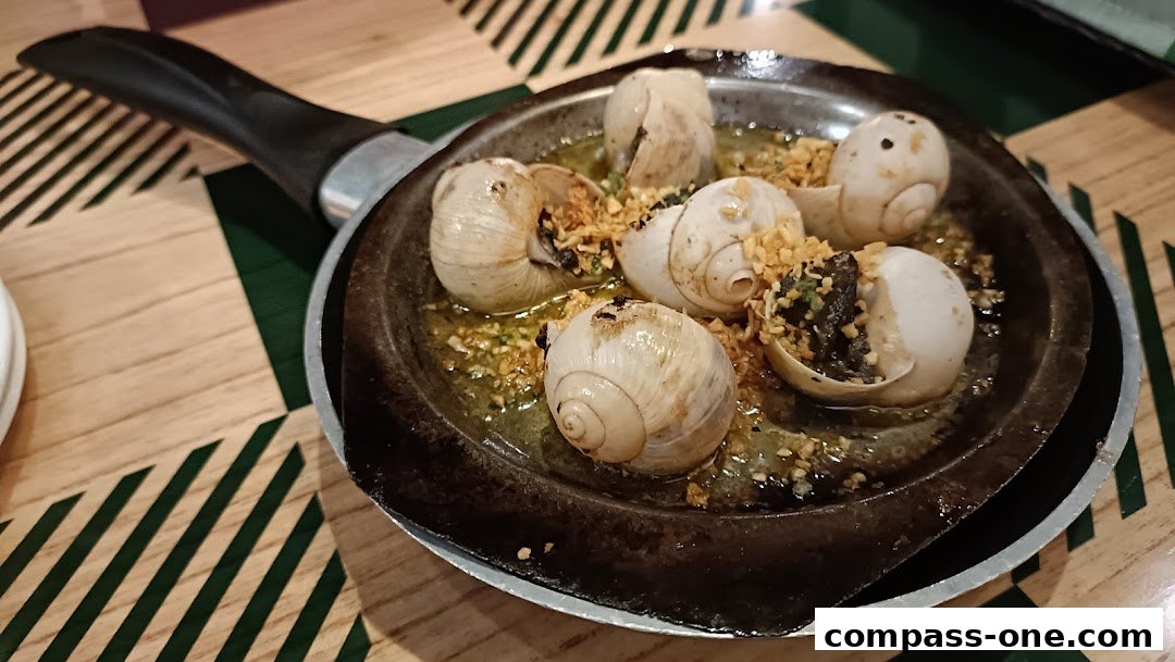 A sizzling pan of escargots in garlic butter, served in their shells.
