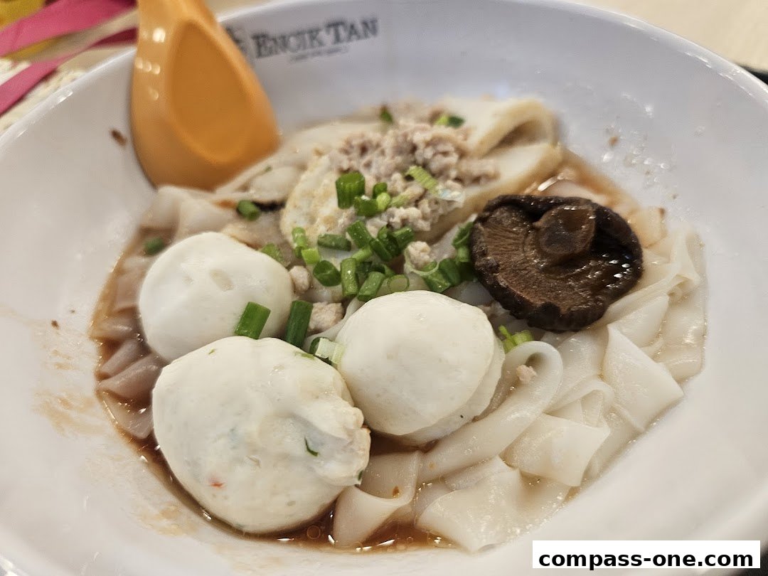 A bowl of noodles with fish balls, minced meat, mushroom, and spring onions.