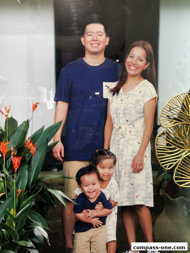 A family of four posing for a photo in front of a shop with plants.