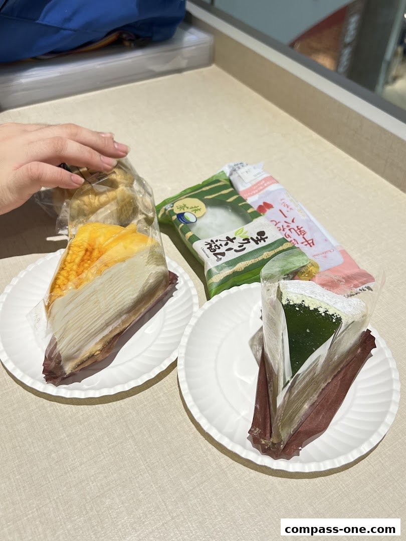 Two slices of cake and packaged sweets are displayed on white plates.