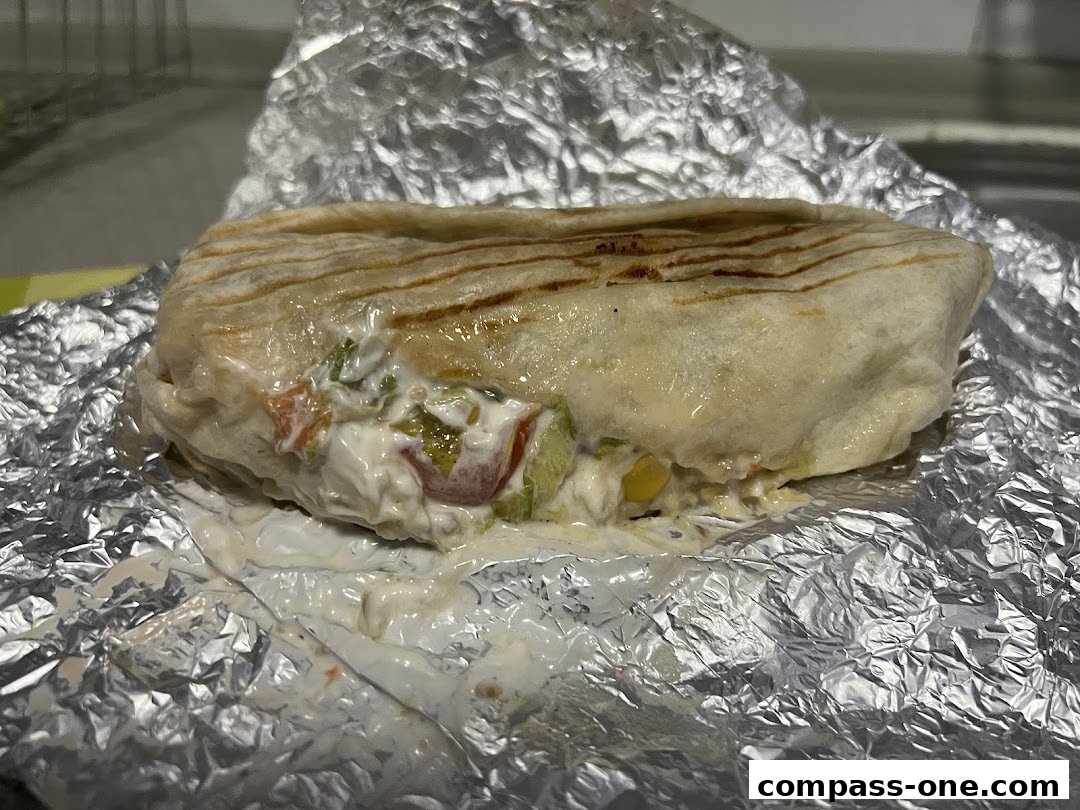 A close-up of a delicious wrap filled with fresh ingredients, served on foil.