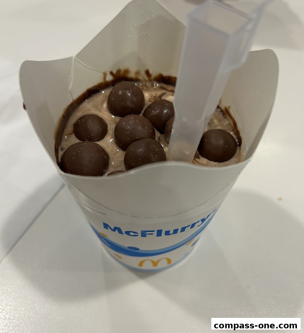 A close-up of a McFlurry dessert with chocolate balls and sauce.