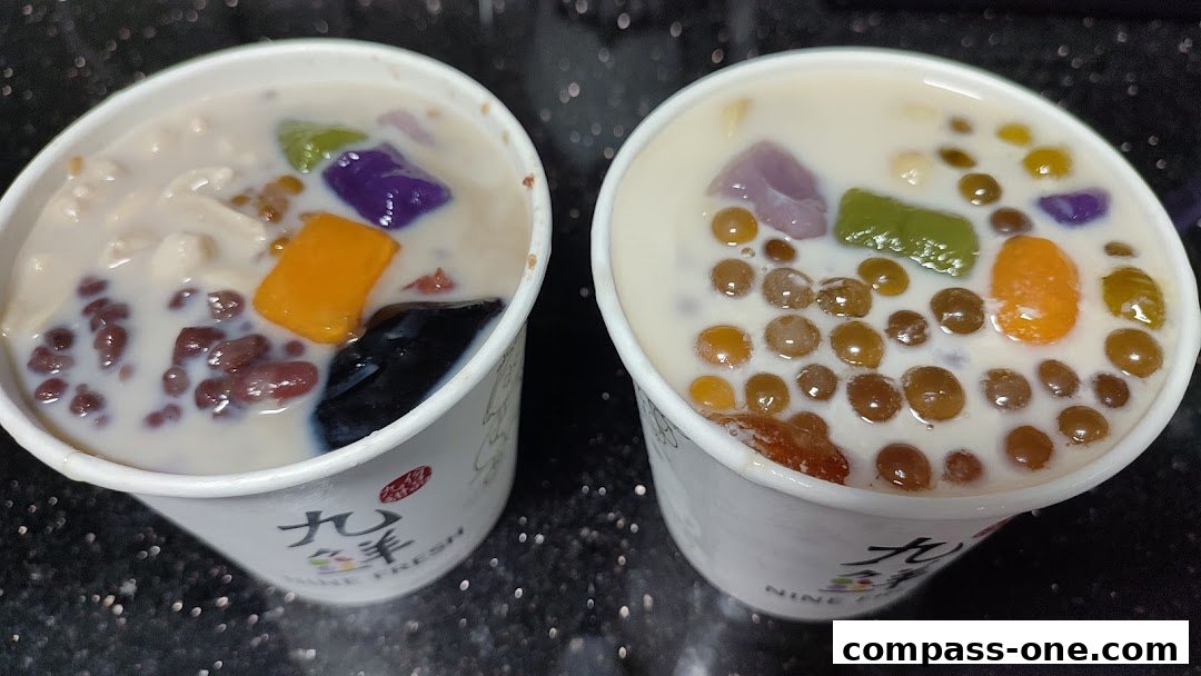 Two cups of Taiwanese desserts with various toppings like taro balls, red beans, and grass jelly.