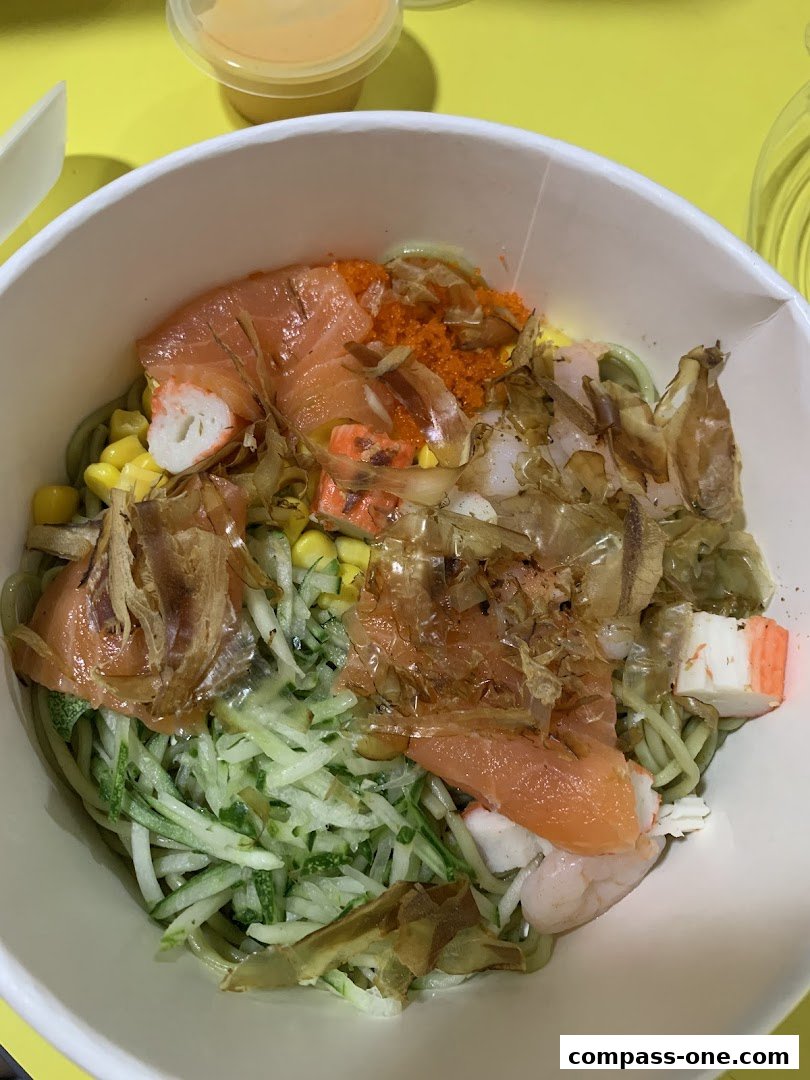 A bowl of Japanese-style cold noodles with salmon, crab sticks, shrimp, and tobiko.