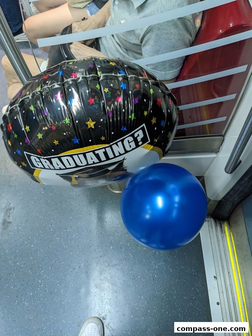 A graduation-themed balloon and a blue balloon are on the floor next to a seat.