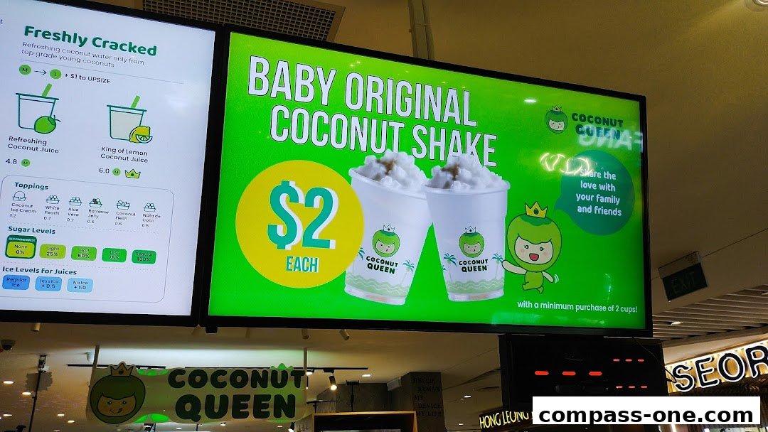 A digital menu board displays a promotion for Baby Original Coconut Shake at Coconut Queen.