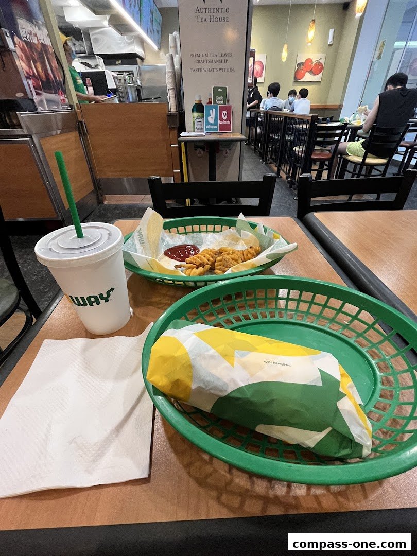 A Subway meal with a sandwich, fries, and a drink on a table.