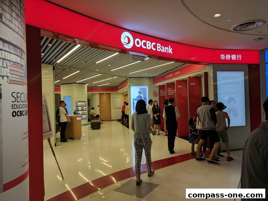 Interior view of an OCBC Bank branch with customers and ATMs visible.