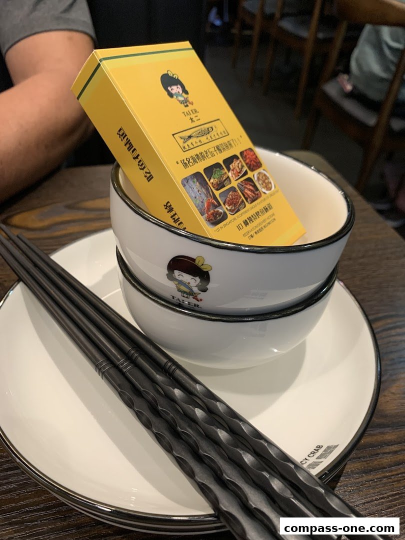 A table setting with bowls, chopsticks, and a yellow box from Fu Qi Grilled Fish.