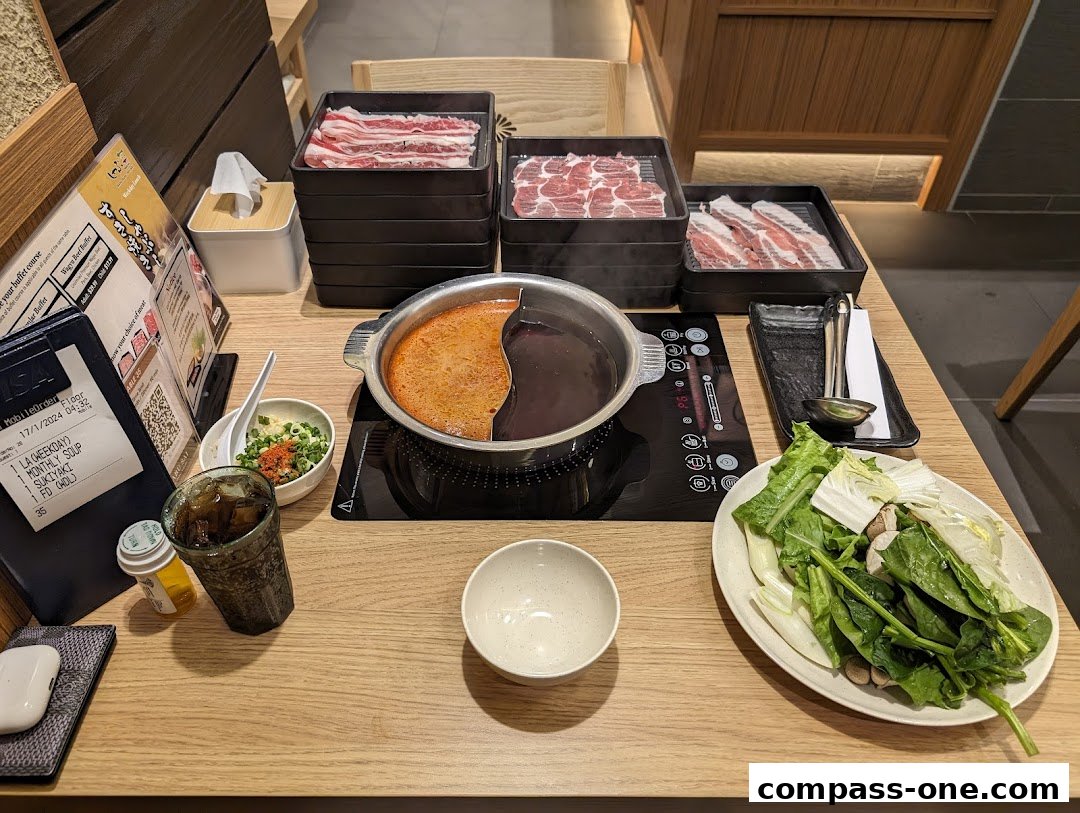 A table set for a Shabu Sai meal with hot pot, assorted meats, and fresh vegetables.