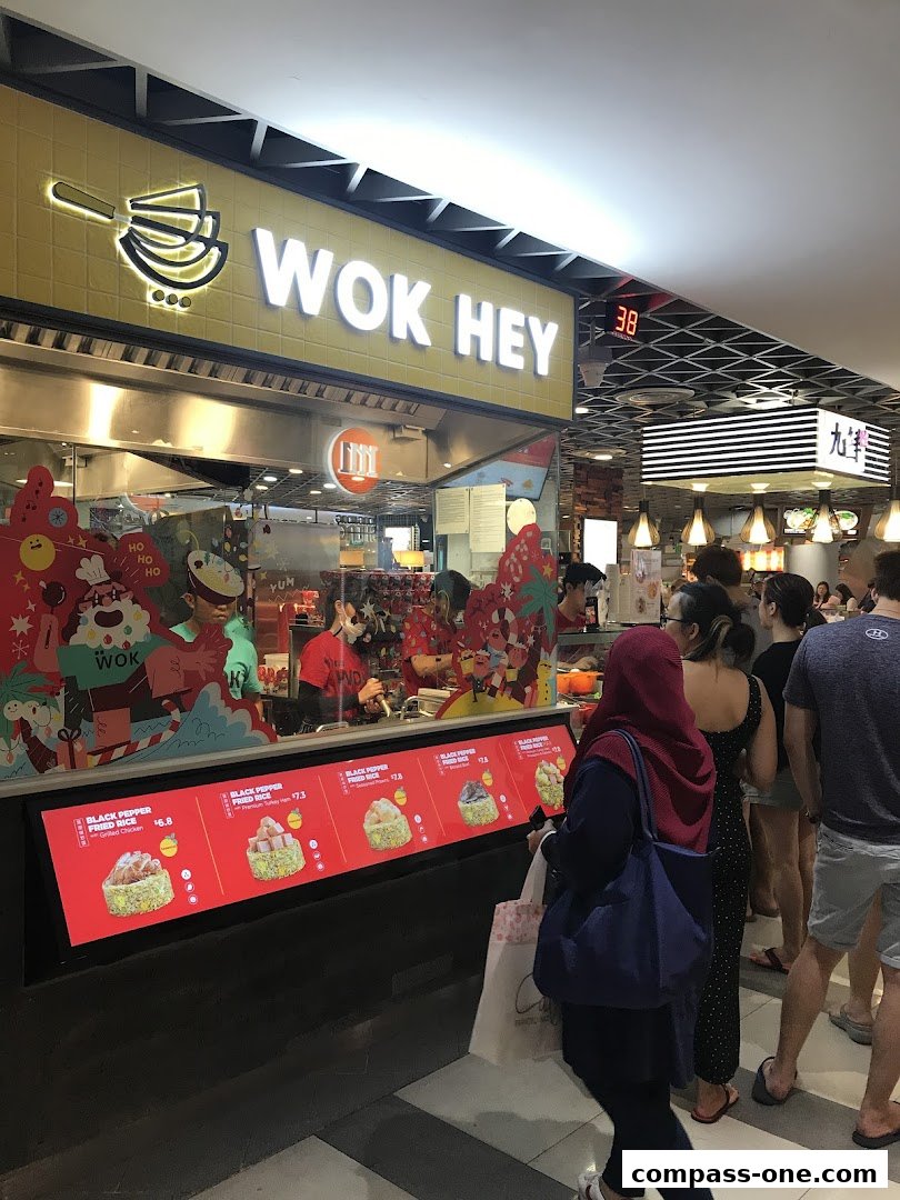 Customers queue at Wok Hey, a food stall displaying its menu with various fried rice options.