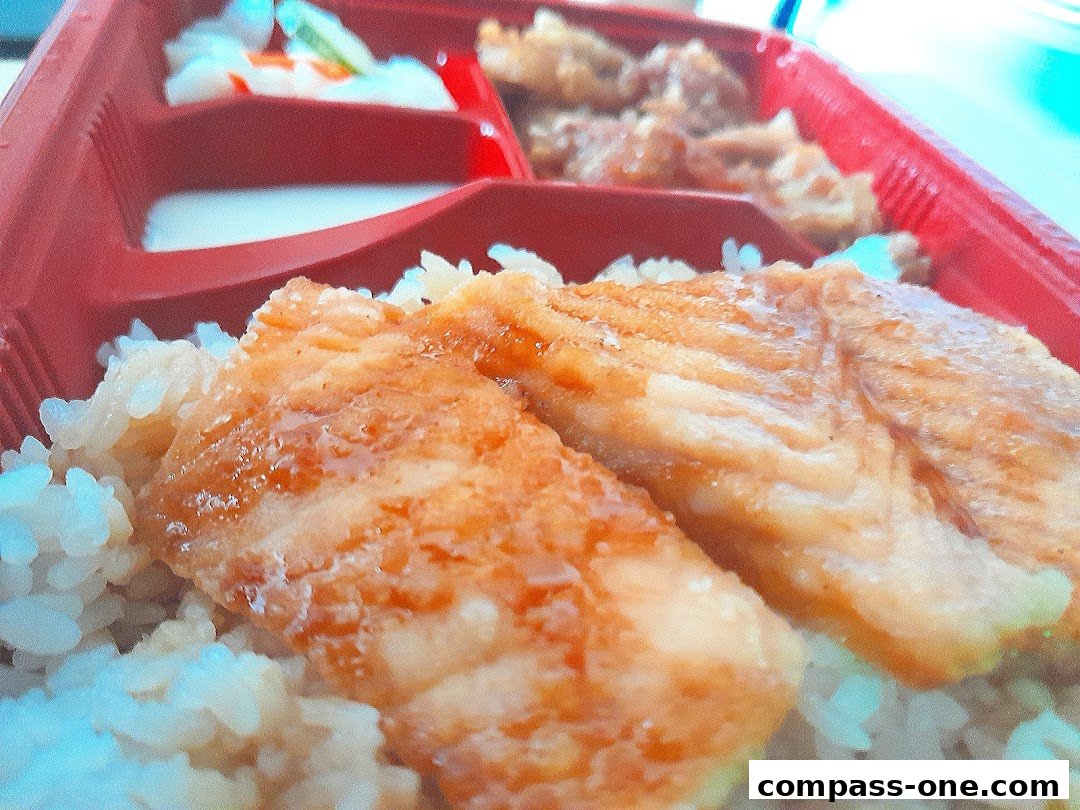 A close-up of a bento box with rice and fried fish fillets.