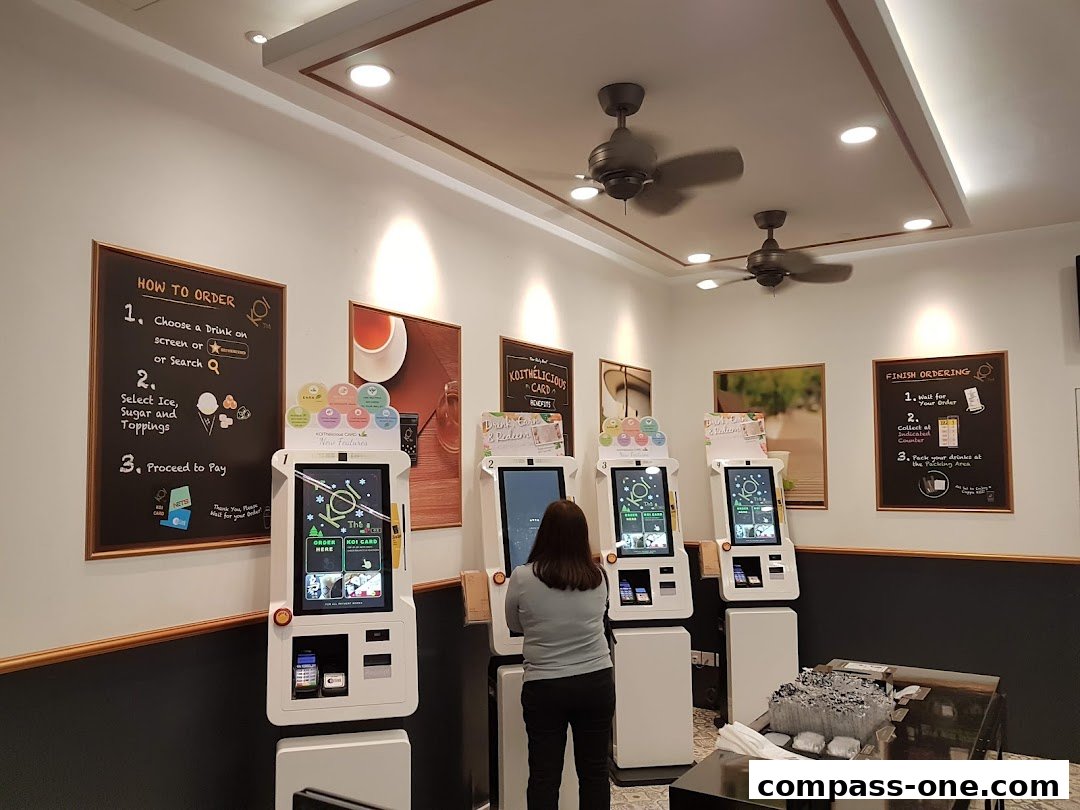 Customers ordering drinks at self-service kiosks in a KOI Thé shop.
