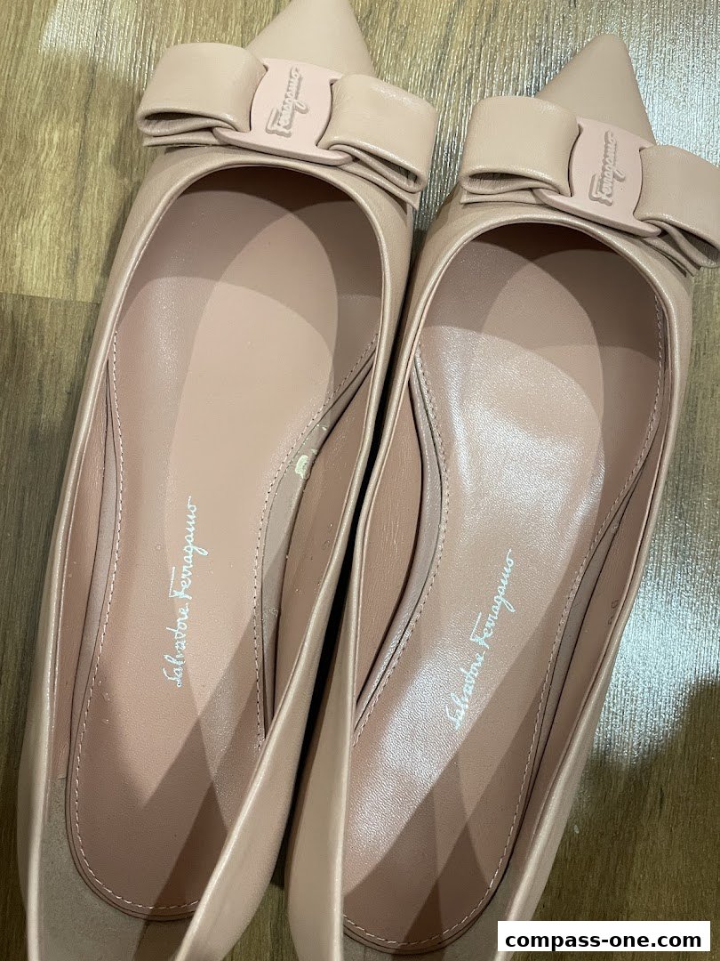A pair of elegant, nude-colored Salvatore Ferragamo ballet flats with signature bow detail.