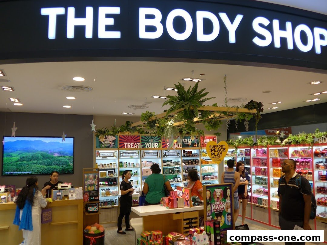 Interior view of The Body Shop store with products displayed and customers browsing.