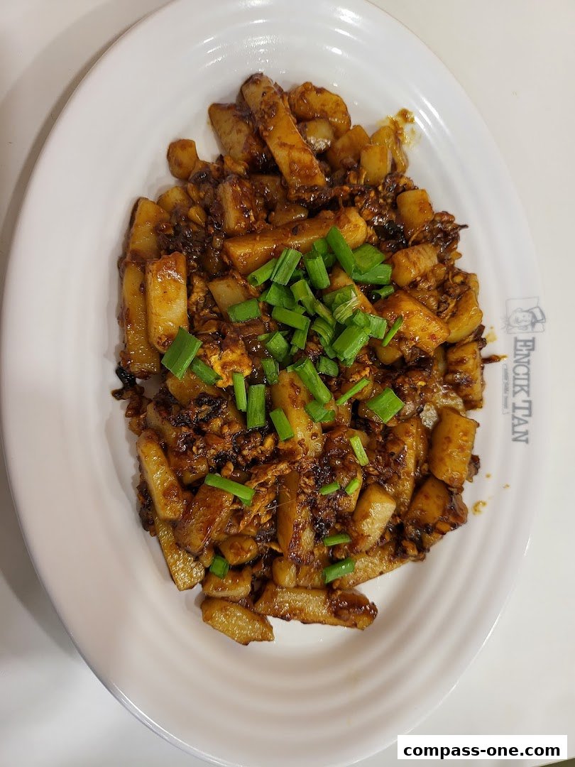 A plate of stir-fried carrot cake topped with chopped green onions.
