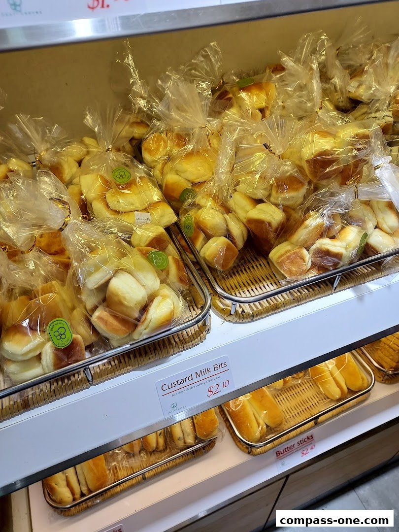 A display of freshly baked bread rolls and buns in plastic packaging at a bakery.