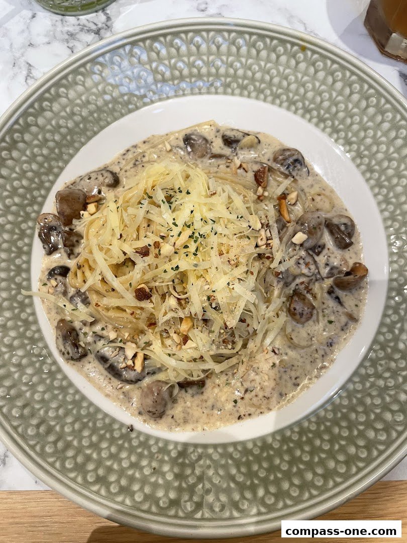 A plate of creamy mushroom pasta topped with shredded cheese and chopped nuts.