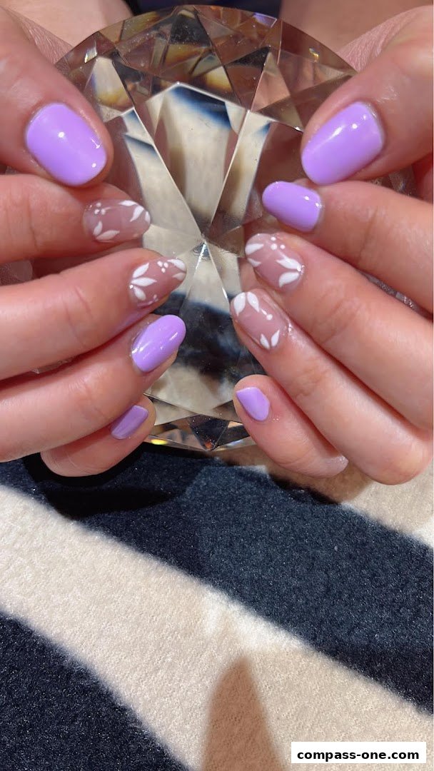 Close-up of hands with lavender and floral nail art, holding a crystal.
