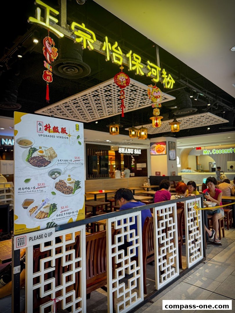 A sign displays food items and prices outside a restaurant with customers seated inside.