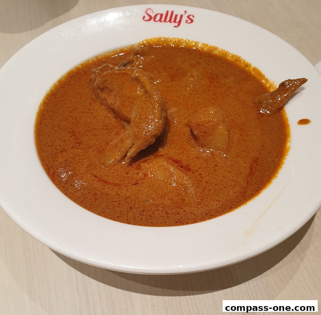 A close-up of a bowl of curry with chicken pieces and potatoes.