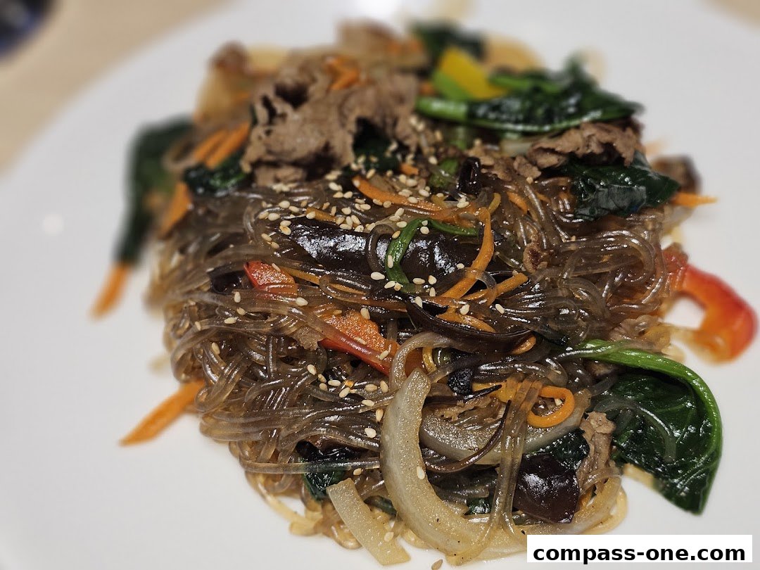 A close-up shot of a delicious plate of Japchae, a Korean glass noodle dish.