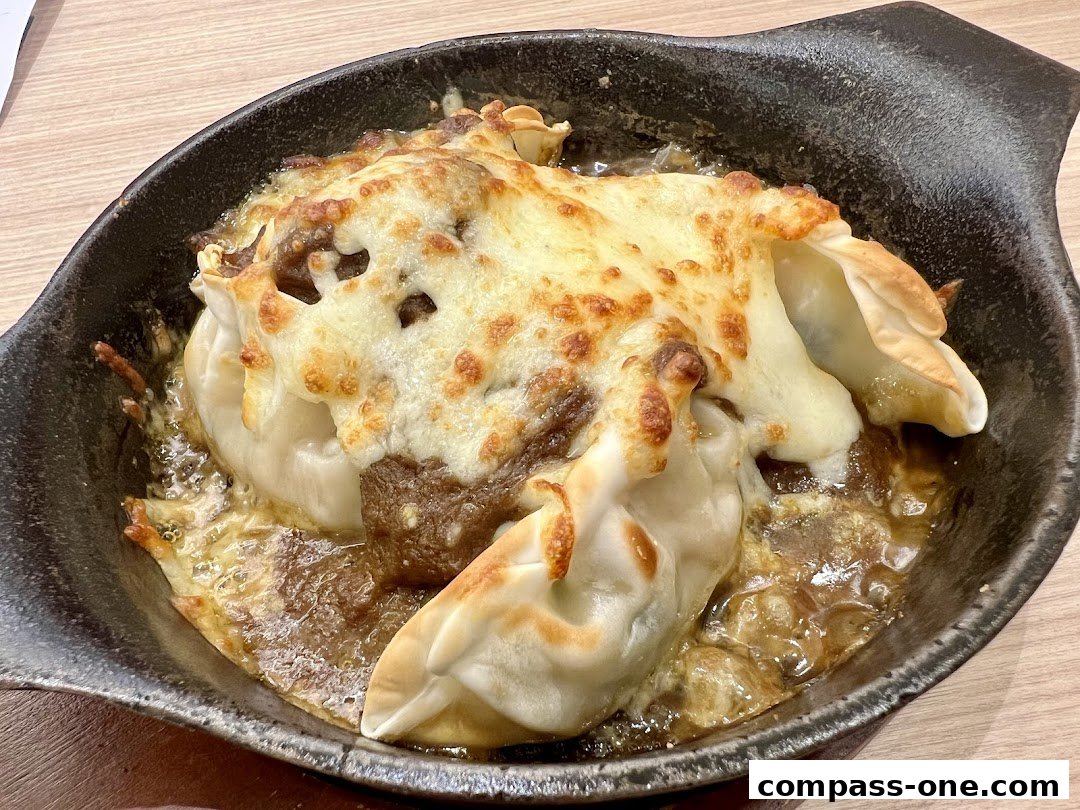A close-up shot of a baked dish with dumplings and melted cheese in a black bowl.