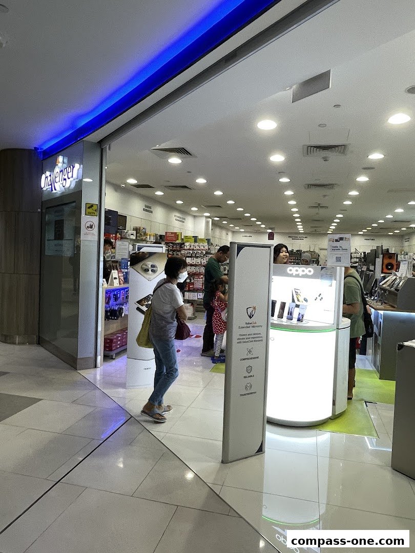 People browsing inside a brightly lit Challenger electronics store with displays of phones and accessories.