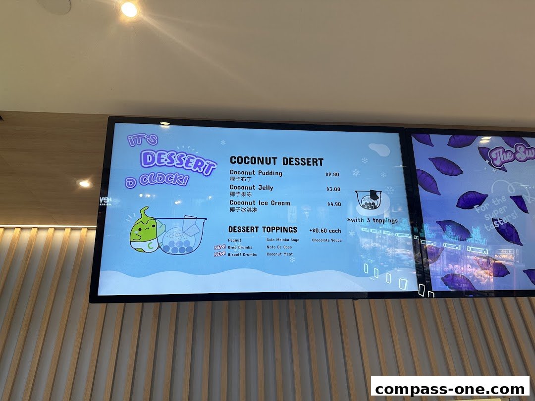 A digital menu board displaying coconut desserts and toppings with prices.
