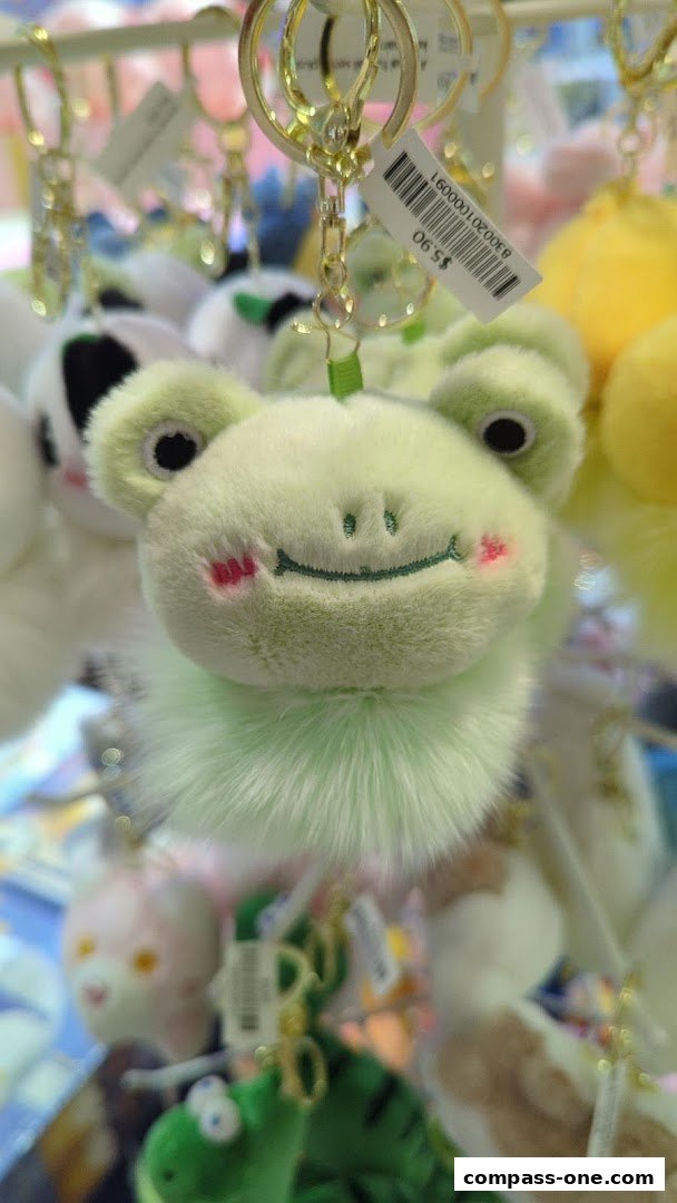 Close-up of a fluffy green frog keychain with pink cheeks and a fluffy tail.