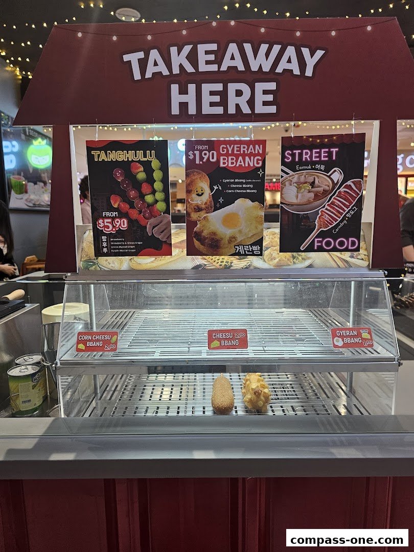A takeaway counter displaying Korean street food items like Tanghulu, Gyeran Bbang, and Corndogs.