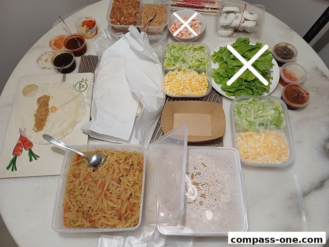 A table laden with ingredients for popiah, including wrappers, shredded vegetables, and sauces.
