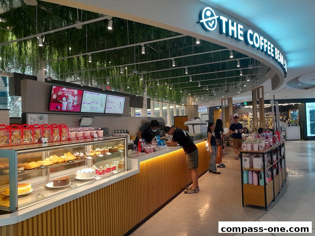 Interior view of The Coffee Bean & Tea Leaf shop with display cases of pastries and customers ordering.